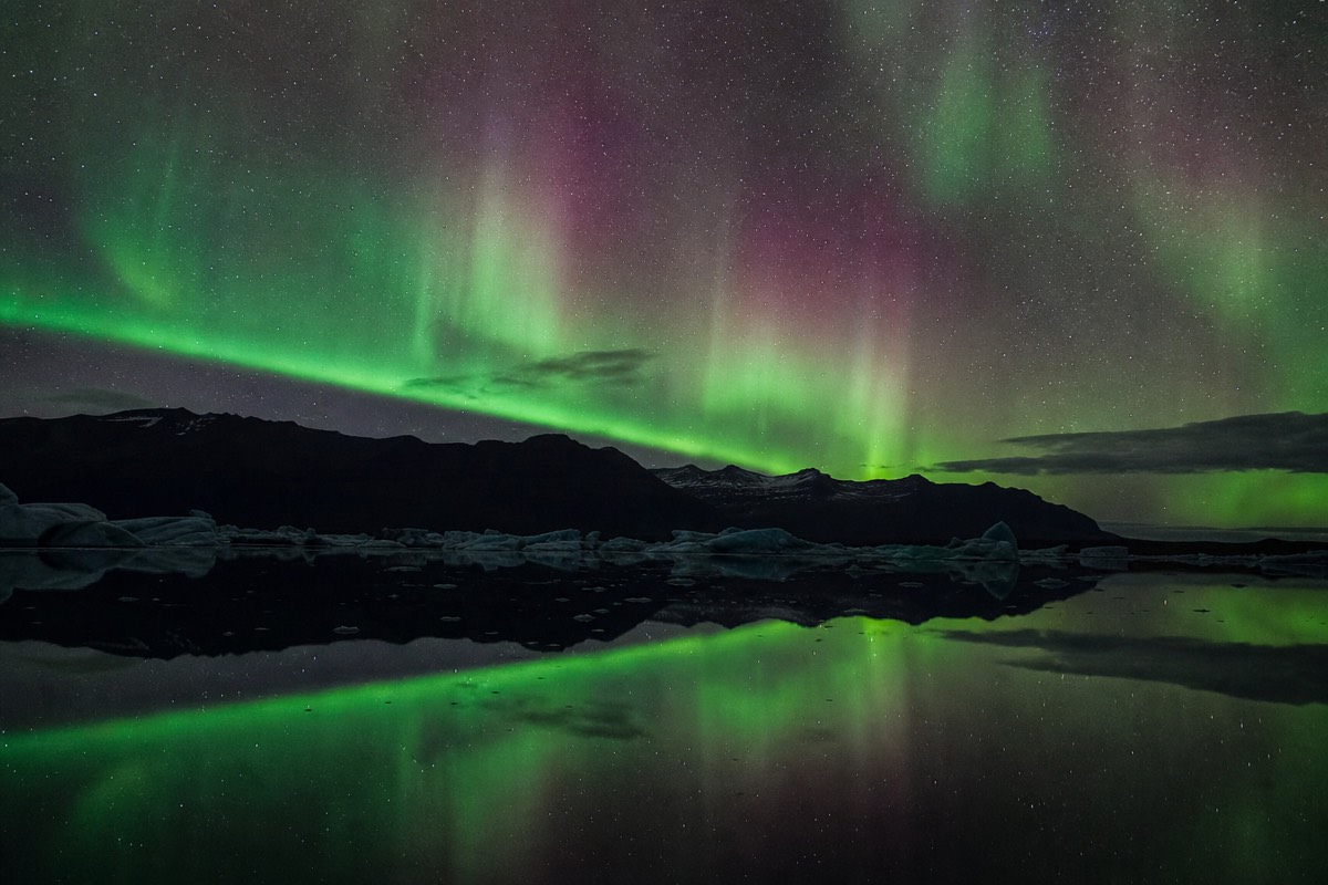 The Northern Lights in Iceland reflected in a still lagoon at night