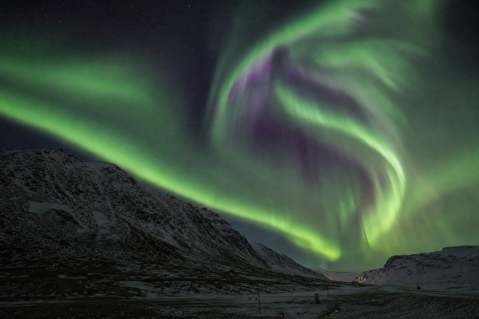 Green aurora in Iceland stretching across a starry night sky